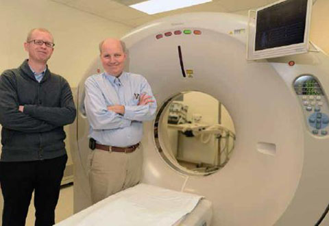 2 doctors stand next to a CT scanner